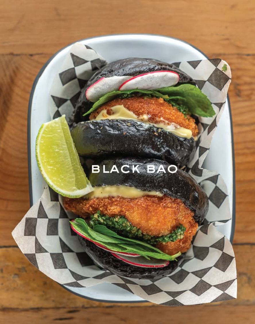 Two charcoal bao buns filled with crispy katsu, greens and pickled radish