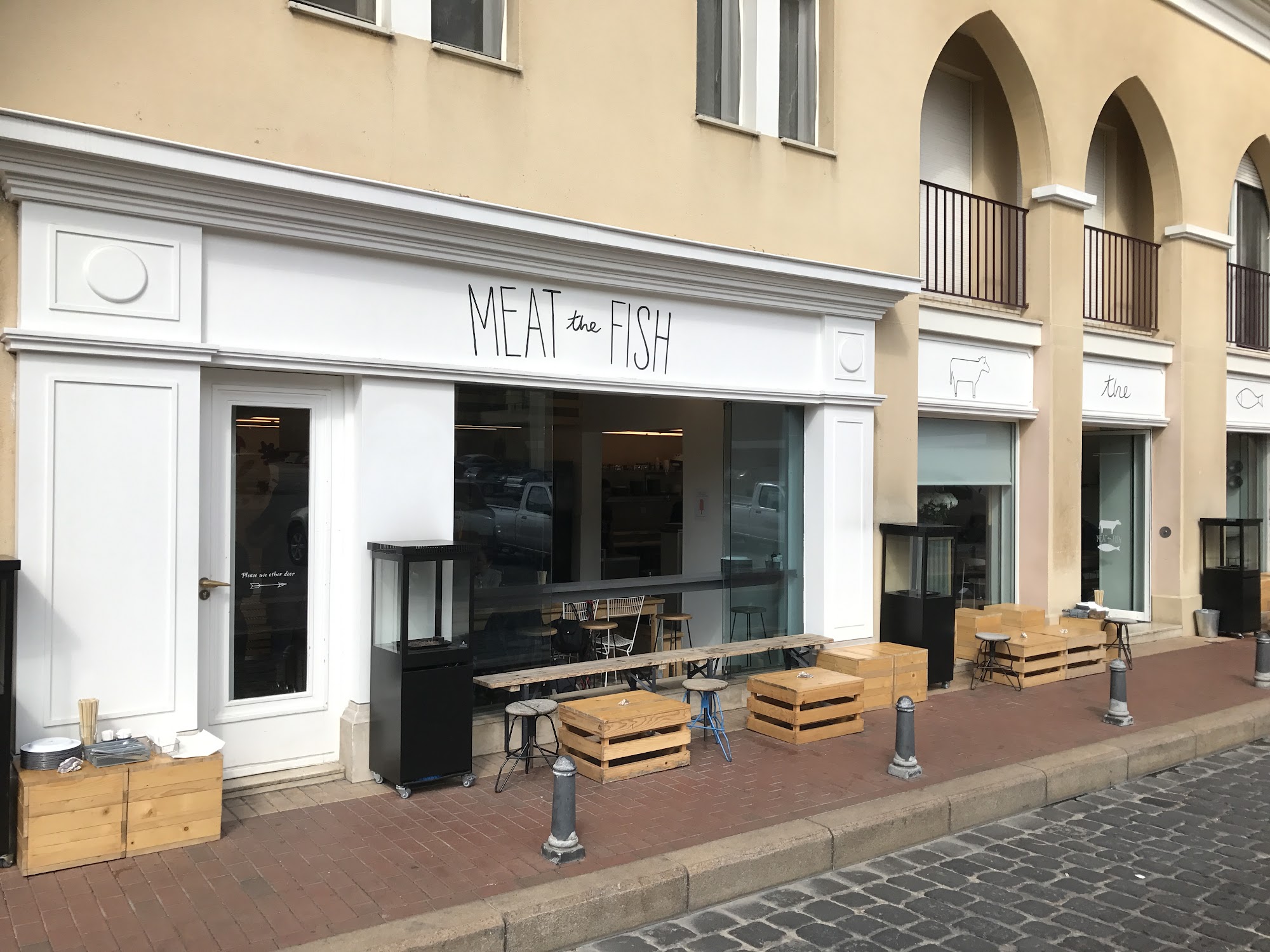 The Meat the Fish facade: hand written signage, slate blue shutters and the black and white diners mural framed by painted flowers