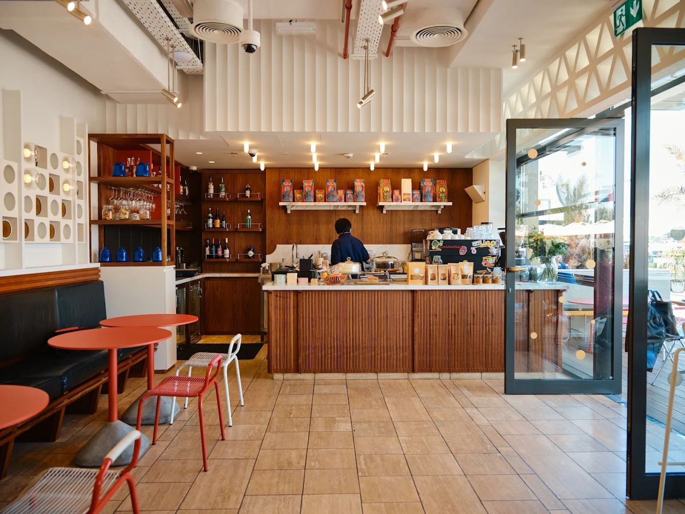The Dubai interior: warm wood counter, marble top, coral chairs and shelves of pantry goods