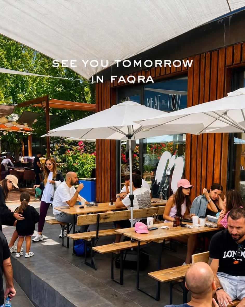 The Faqra terrace under sail shades, full of guests on wooden benches
